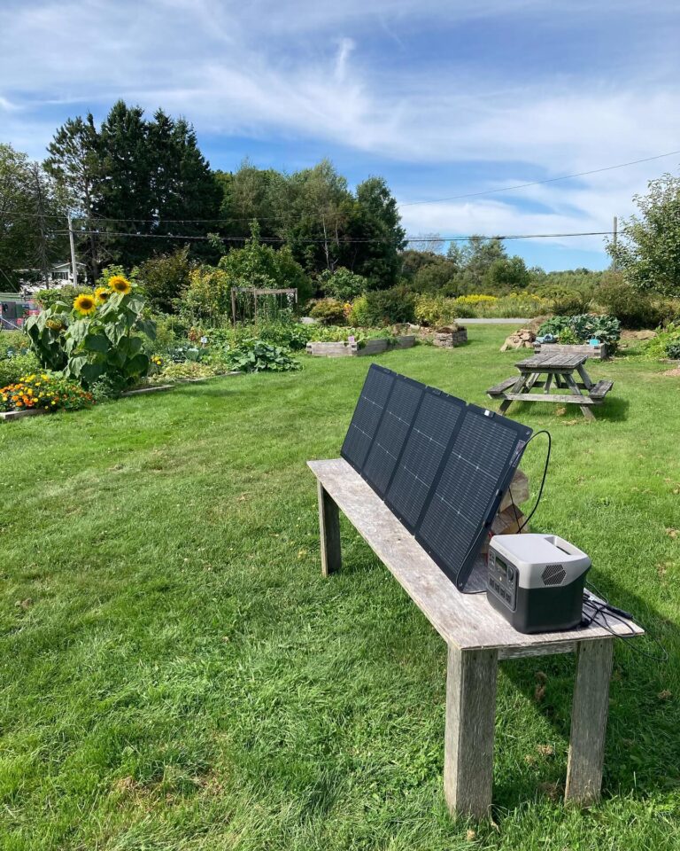 Portable solar panel charging a battery on a bench in a community garden